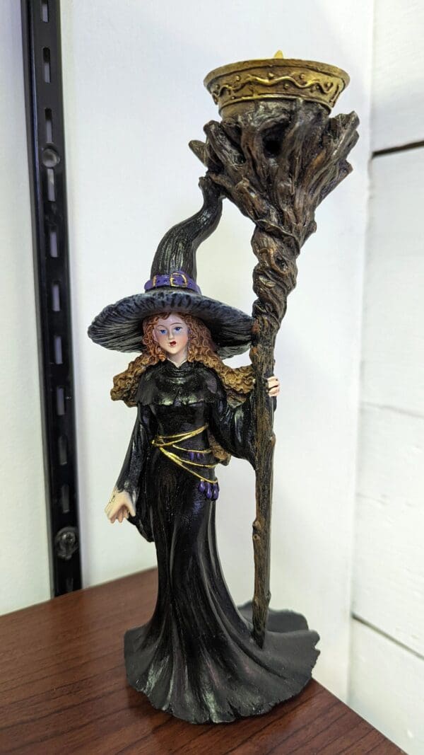 A witch figurine holding a broom and wearing a hat.