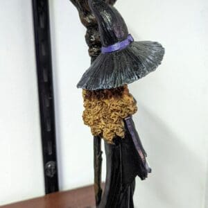 A black statue of a witch with a broom and hat.