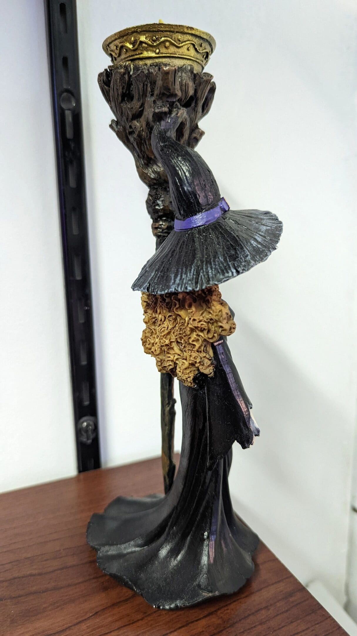 A black statue of a witch with a broom and hat.