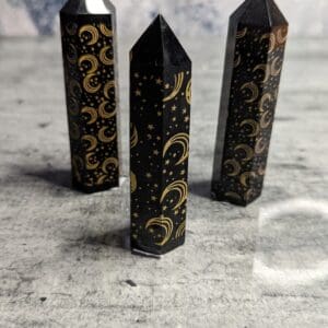 Three black and gold candles on a table.