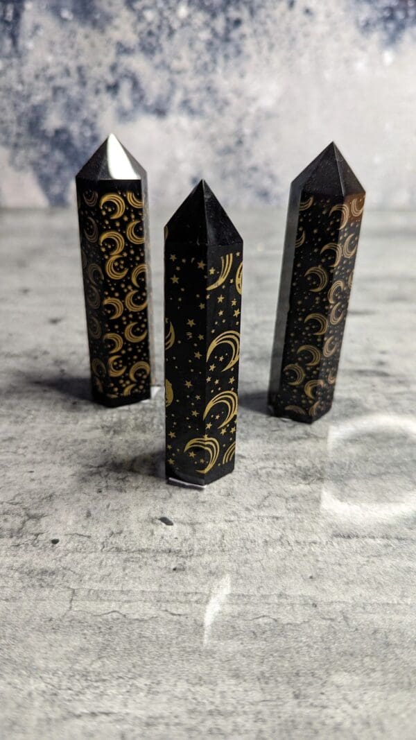 Three black and gold candles on a table.