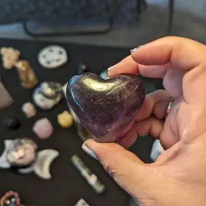 A person holding a heart shaped stone in front of other stones.