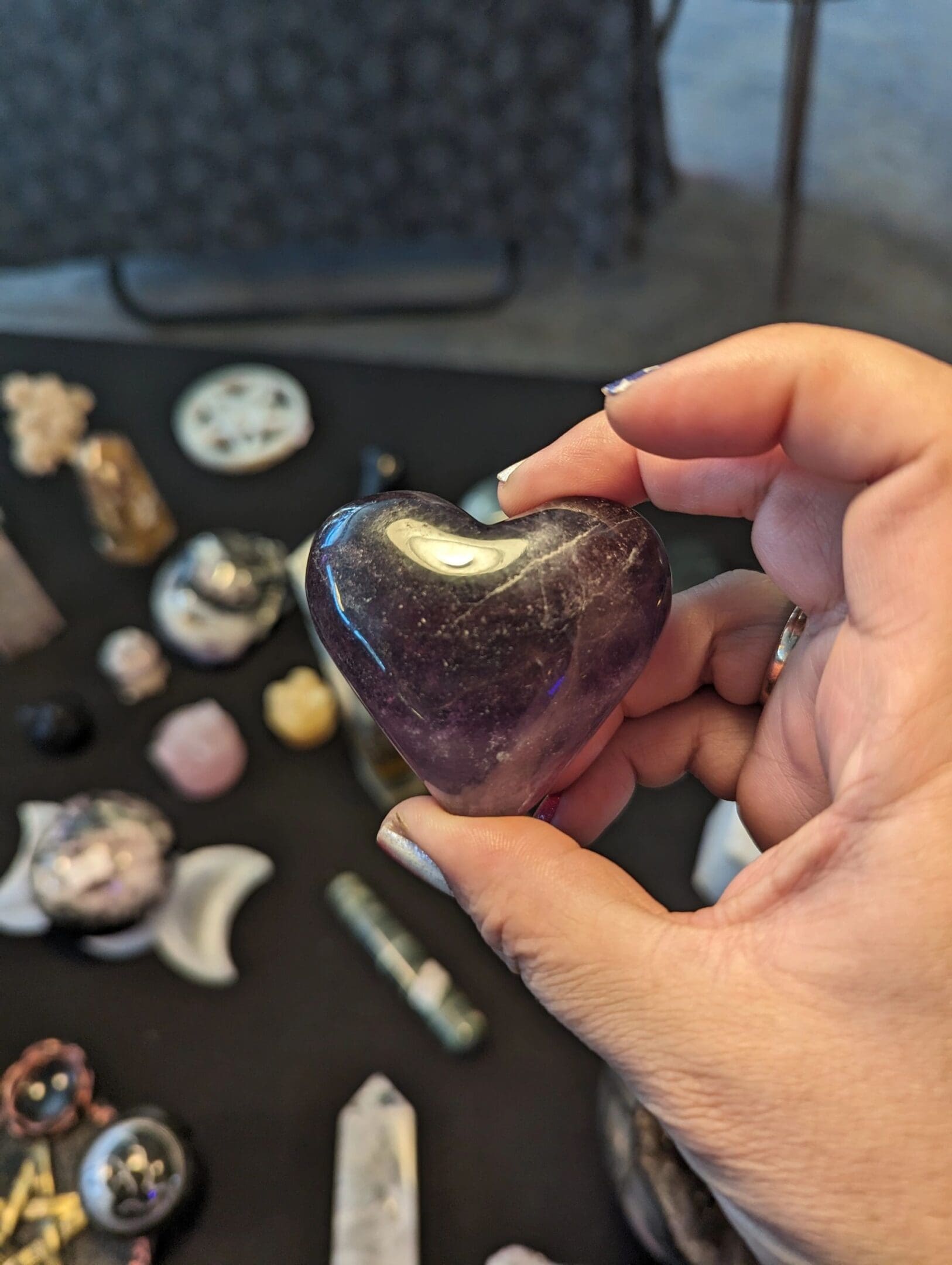 A person holding a heart shaped stone in front of other stones.