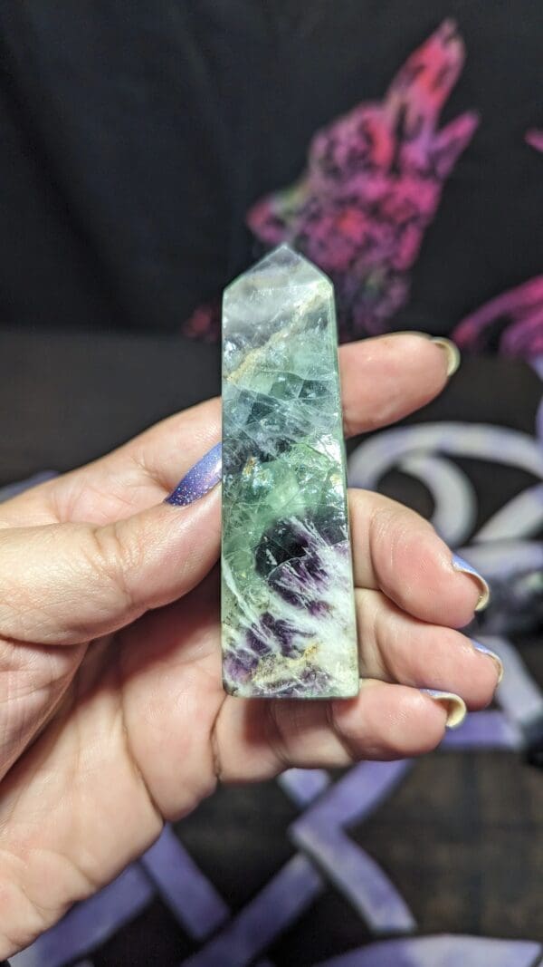 A person holding up a piece of green and purple stone.