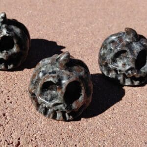 Three metal skulls sitting on the ground.