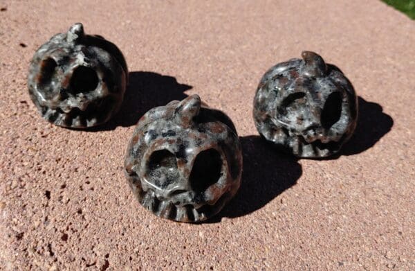 Three metal skulls sitting on the ground.