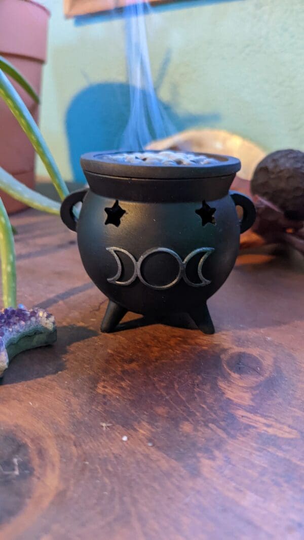 A black pot with three moons and stars on it.