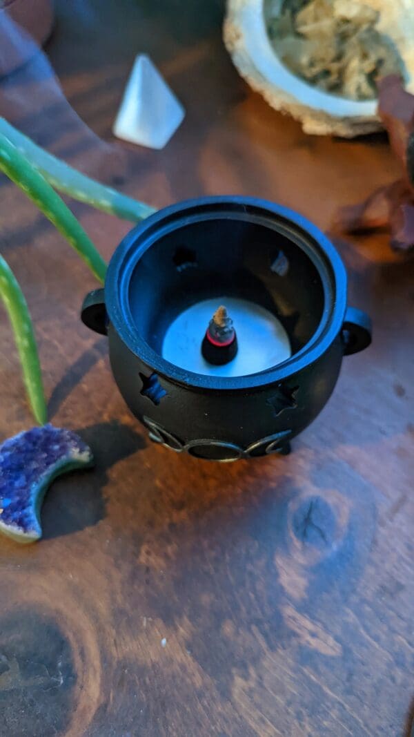 A candle in a black pot on the table