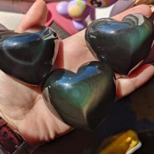 A person holding three heart shaped stones in their hands.