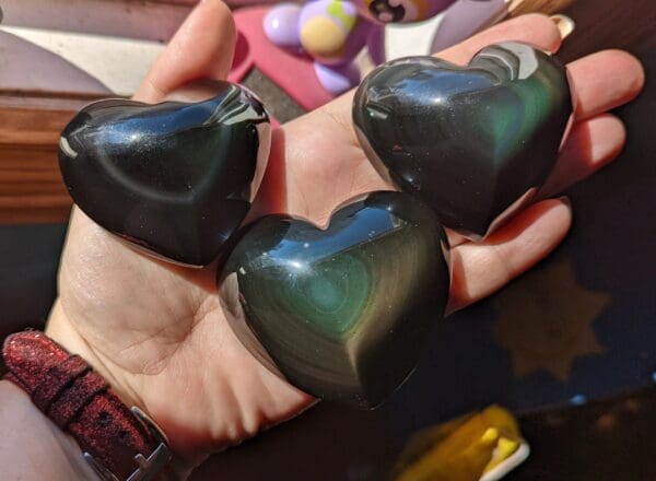 A person holding three heart shaped stones in their hands.