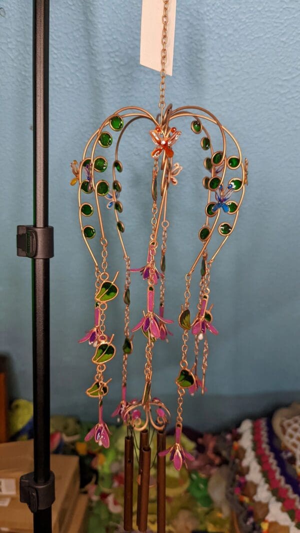 A wind chime with green and pink beads hanging from it.