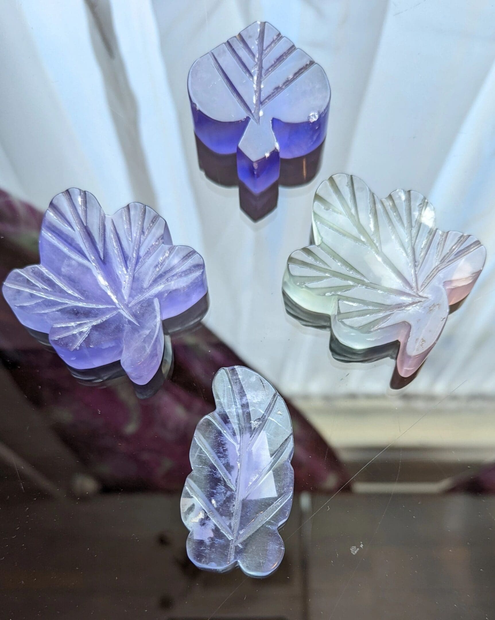 A close up of four glass flowers hanging from the ceiling.