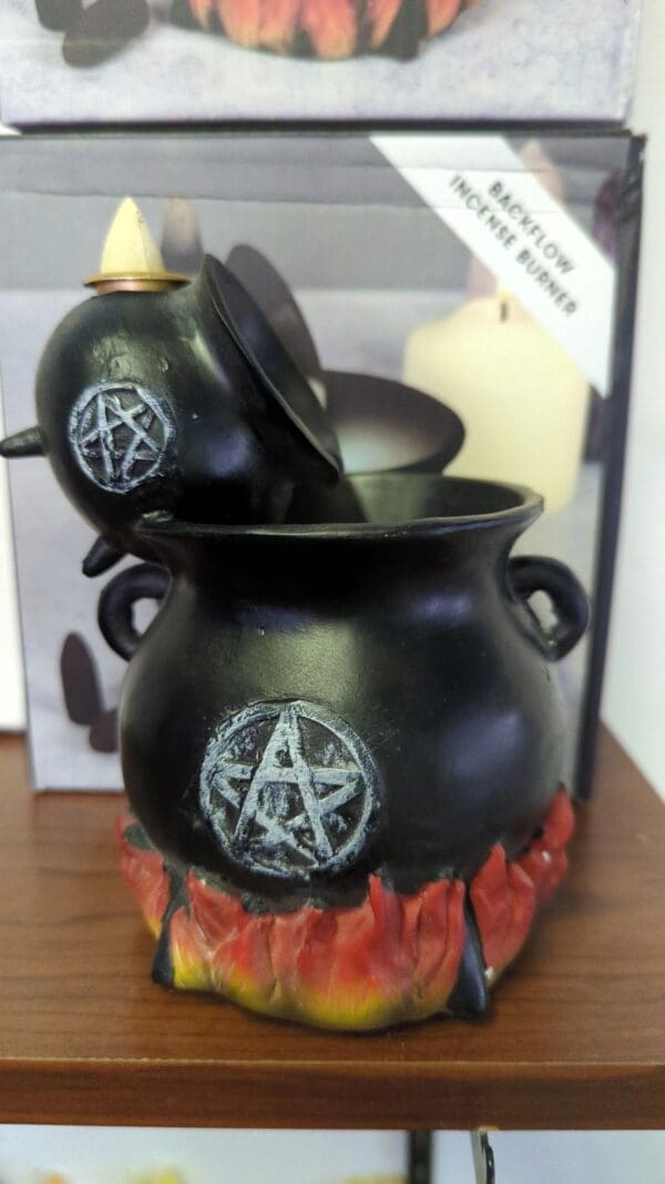 A black pot with a candle and a pentagram on it.