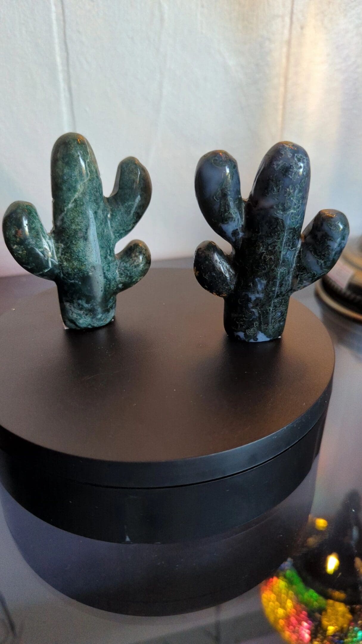 Two green cactus figurines sitting on top of a black box.