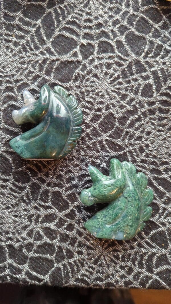 A pair of green and gold horse head earrings.