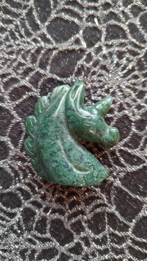 A green stone carving of a horse on the ground.