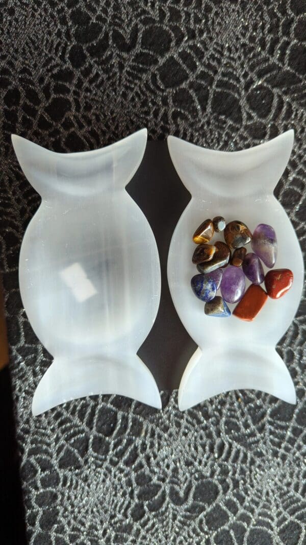 Two white plastic candy dishes with different colored rocks in them.