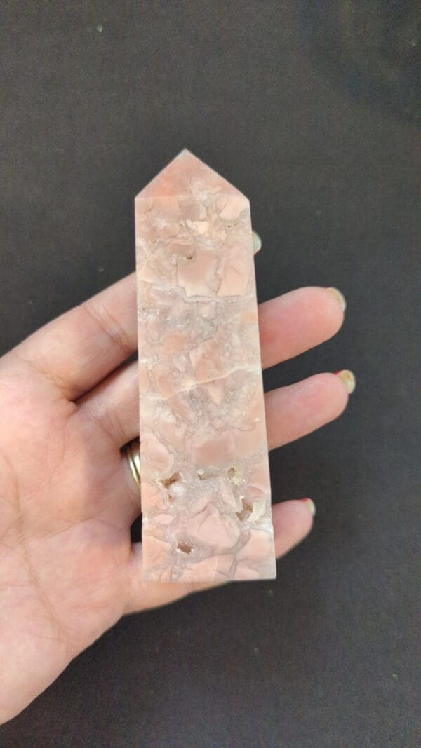 A hand holding a pink stone with white and clear rocks.