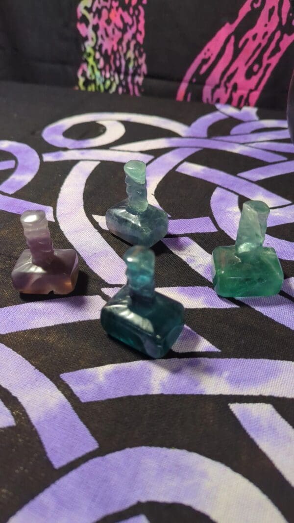 A group of four glass figurines sitting on top of a purple and black table.