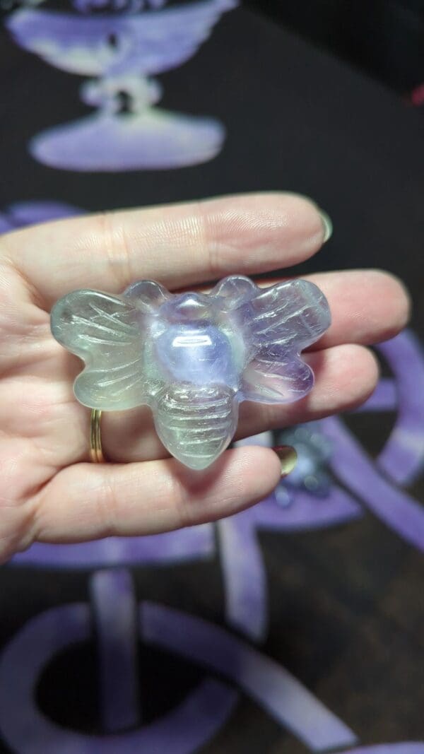 A person holding a small glass bee in their hand.