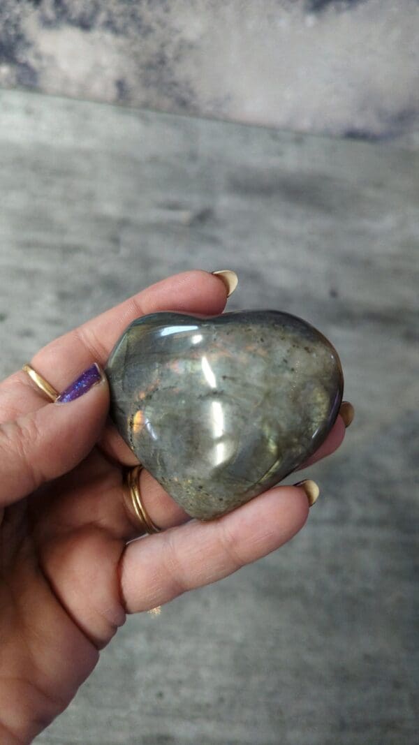 A person holding a heart shaped stone in their hand.