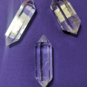 Three clear quartz points on a purple surface.