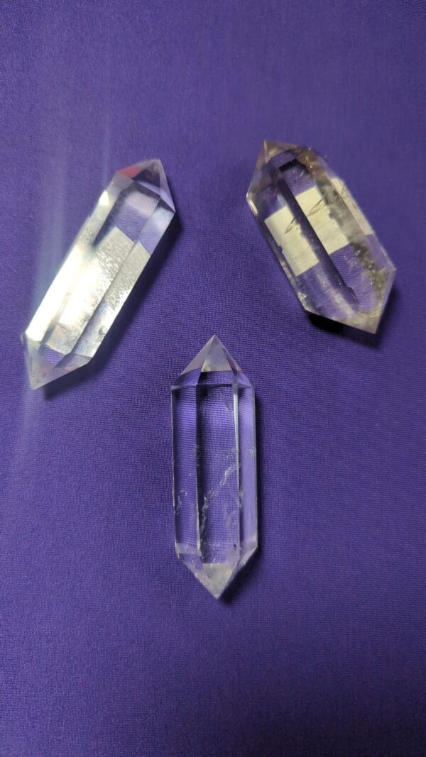 Three clear quartz points on a purple surface.