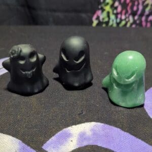 Three black and green figurines sitting on a table.