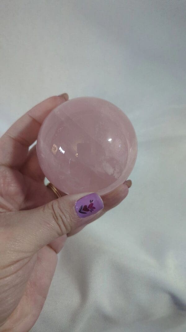 A person holding a pink crystal ball in their hand.