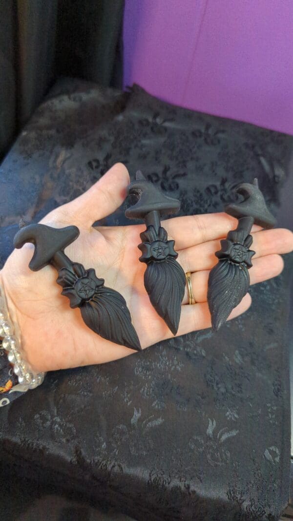 A hand holding four black plastic bats.