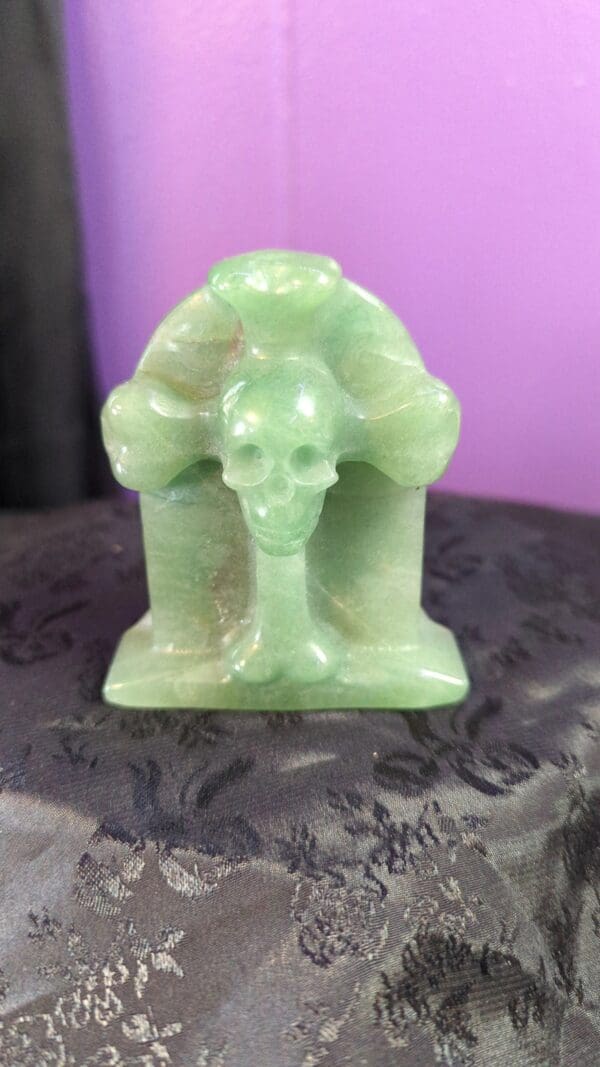 A green stone statue of a skull and hands.