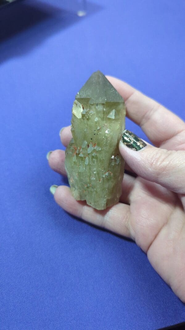 A person holding a green crystal in their hand.