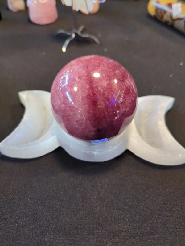 A red stone ball sitting on top of a white stand.