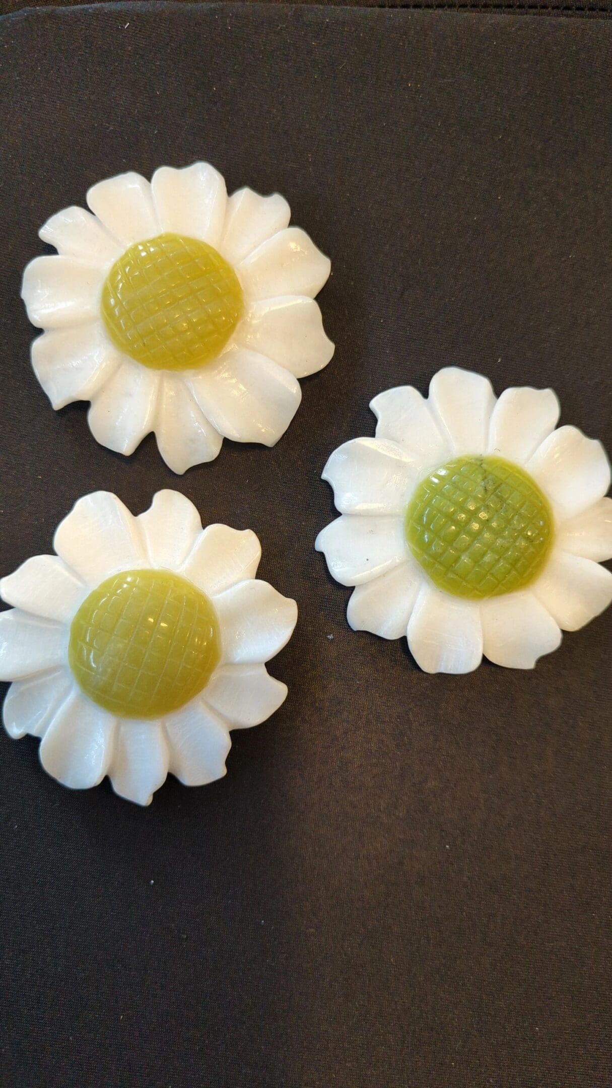 Three white flowers with green centers on a table.