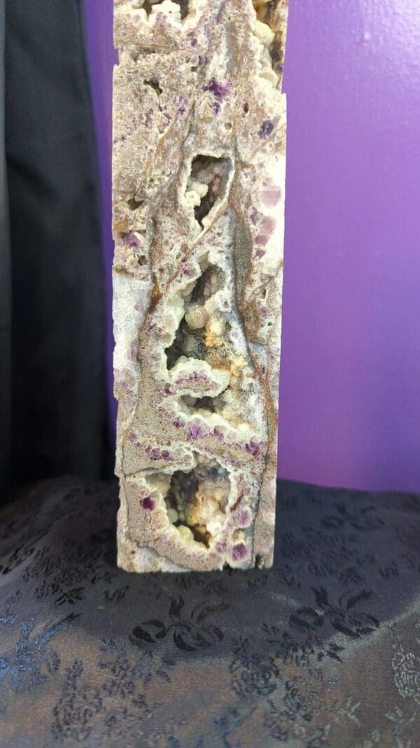 A stone pillar with holes in it and purple wall