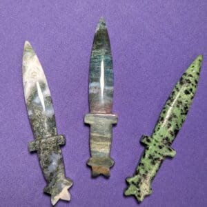 Three knives are shown on a purple surface.