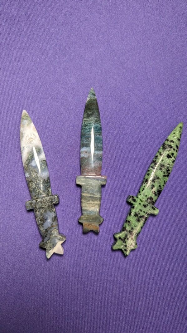 Three knives are shown on a purple surface.