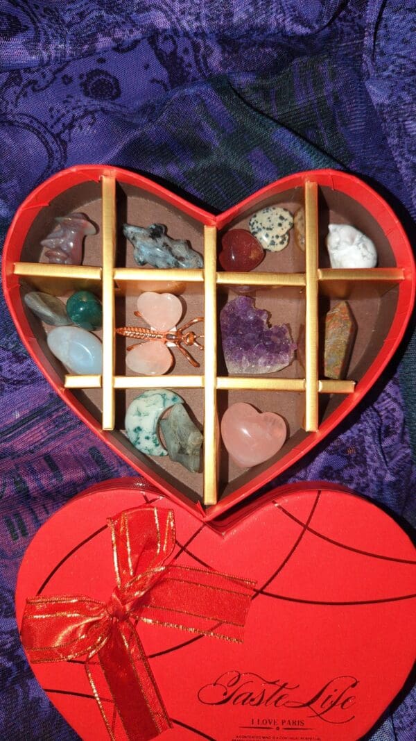 A red heart shaped box filled with lots of rocks.