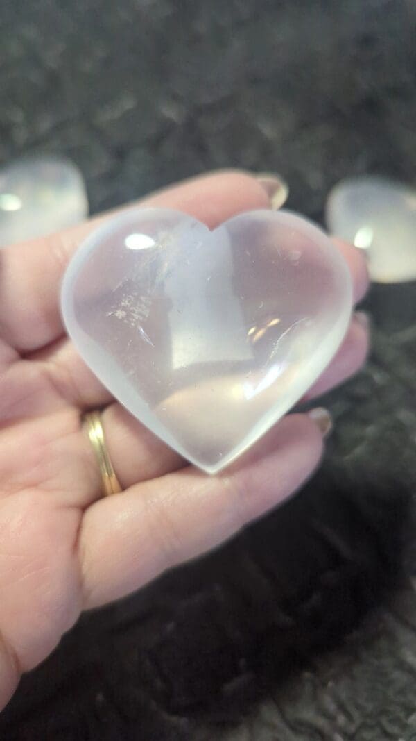 A person holding a heart shaped rock in their hand.