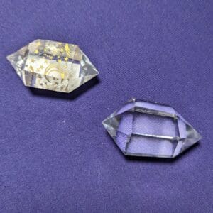 Two pieces of glass are sitting on a purple cloth.