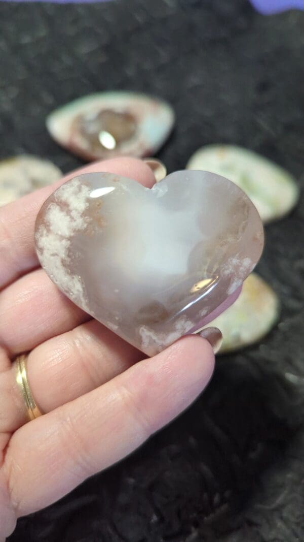 A person holding a heart shaped stone in their hand.