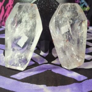 Two crystal skulls sitting on top of a purple table.