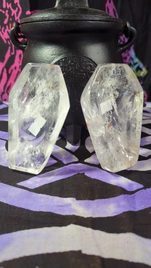 Two crystal skulls sitting on top of a purple table.