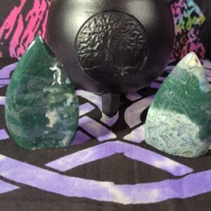 A black pot and some green rocks on top of purple cloth.