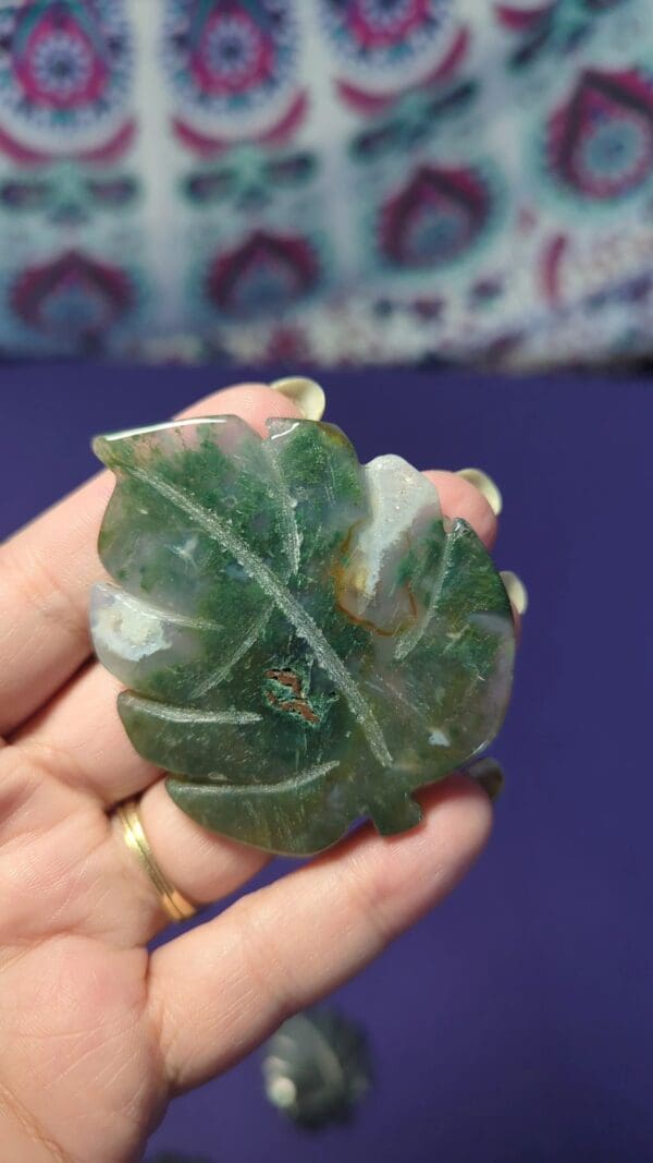 A person holding up a green leaf shaped stone.