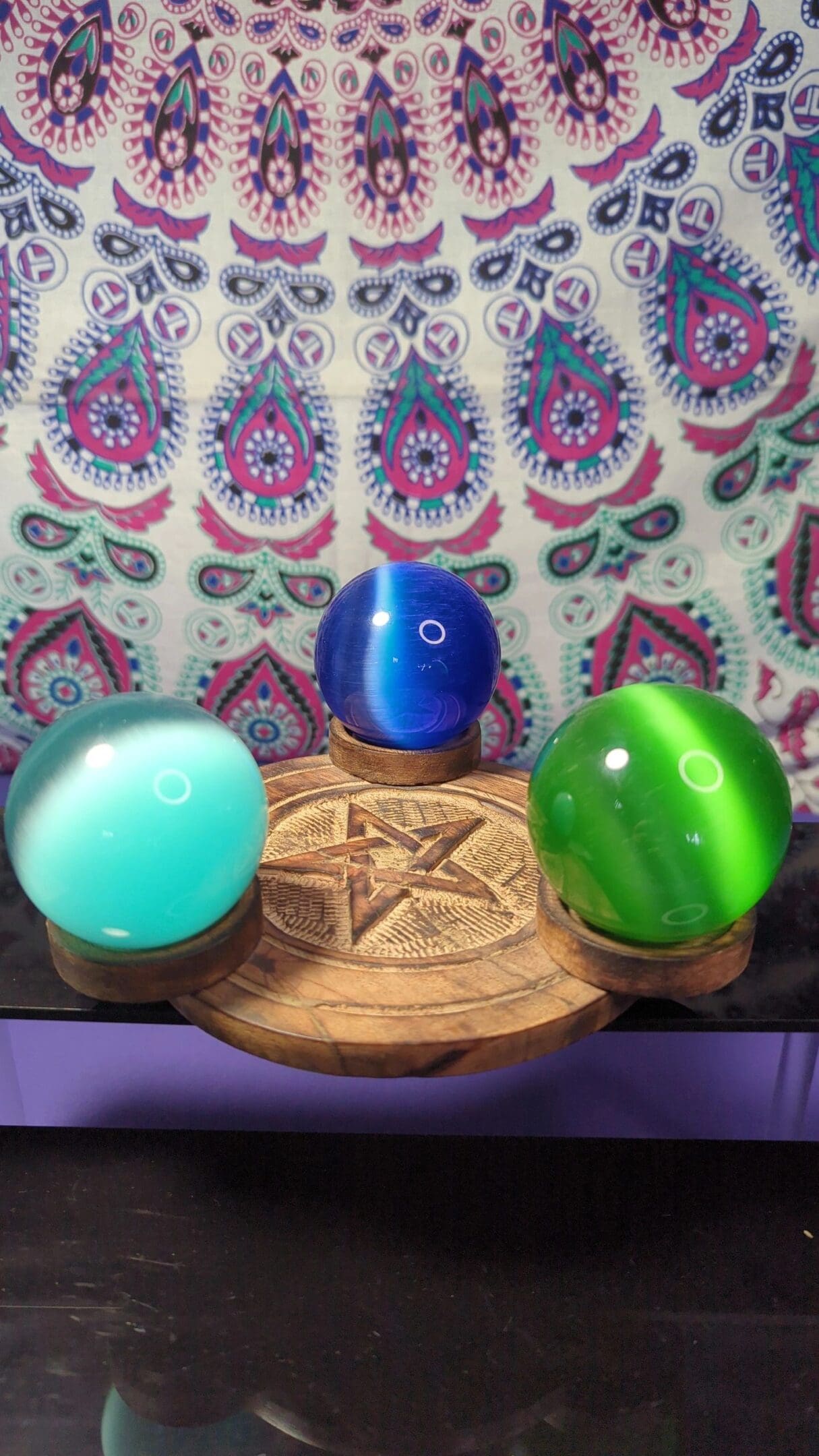 Three different colored balls on a wooden stand.