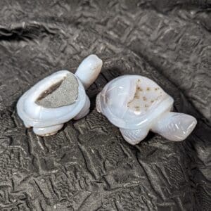 Two white turtle shaped objects sitting on top of a bed.