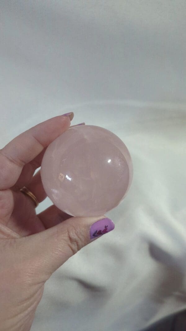 A person holding a pink crystal ball in their hand.