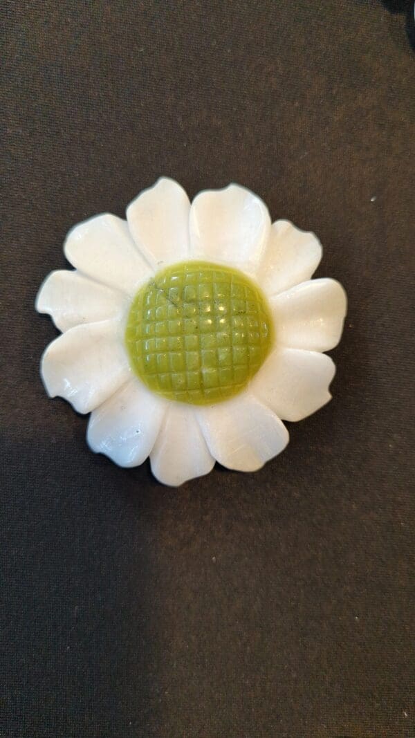 A white flower with green center on top of black table.