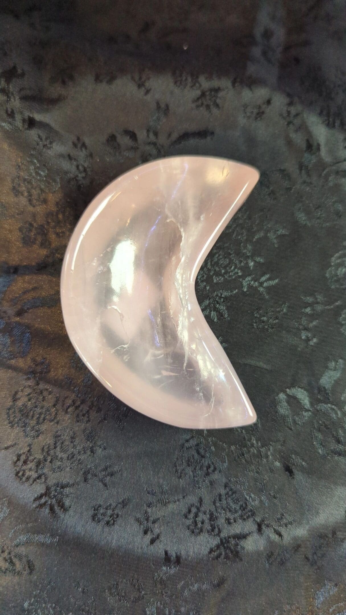 A pink crescent moon shaped dish sitting on top of a table.